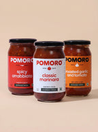 Three jars of Pomoro pasta sauce on a beige background